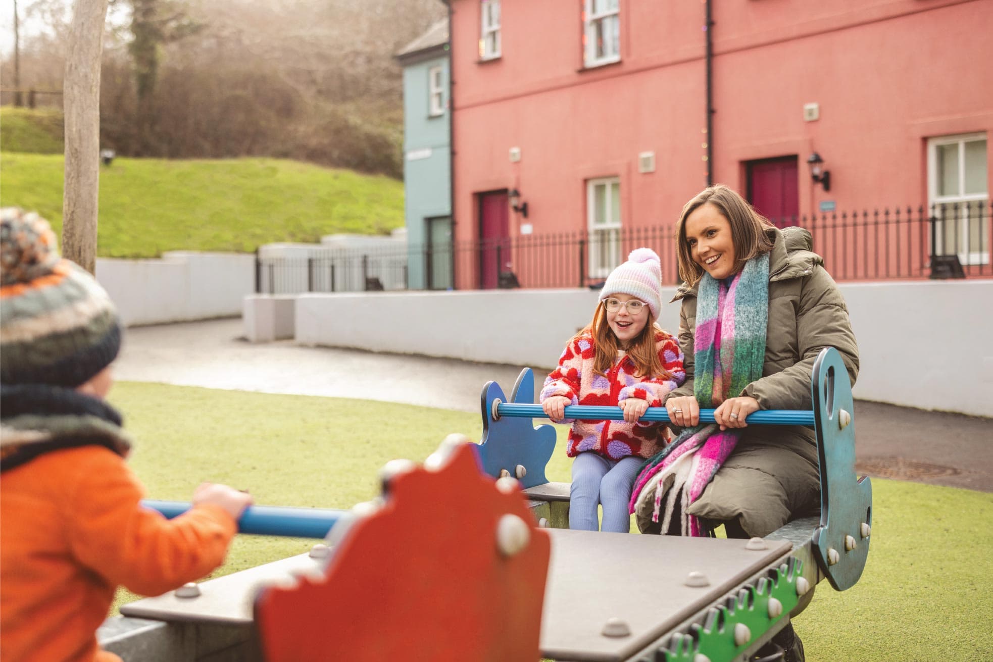 Family On Seesaw In Village Playground