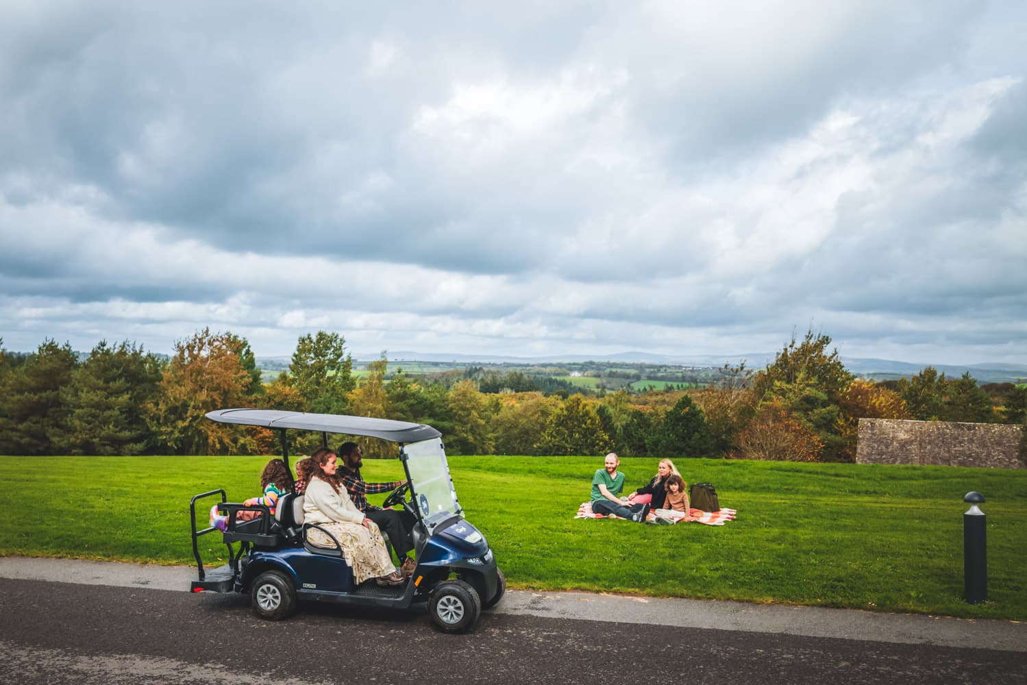 Family On Buggy Driving Past A Family Having A Picnic