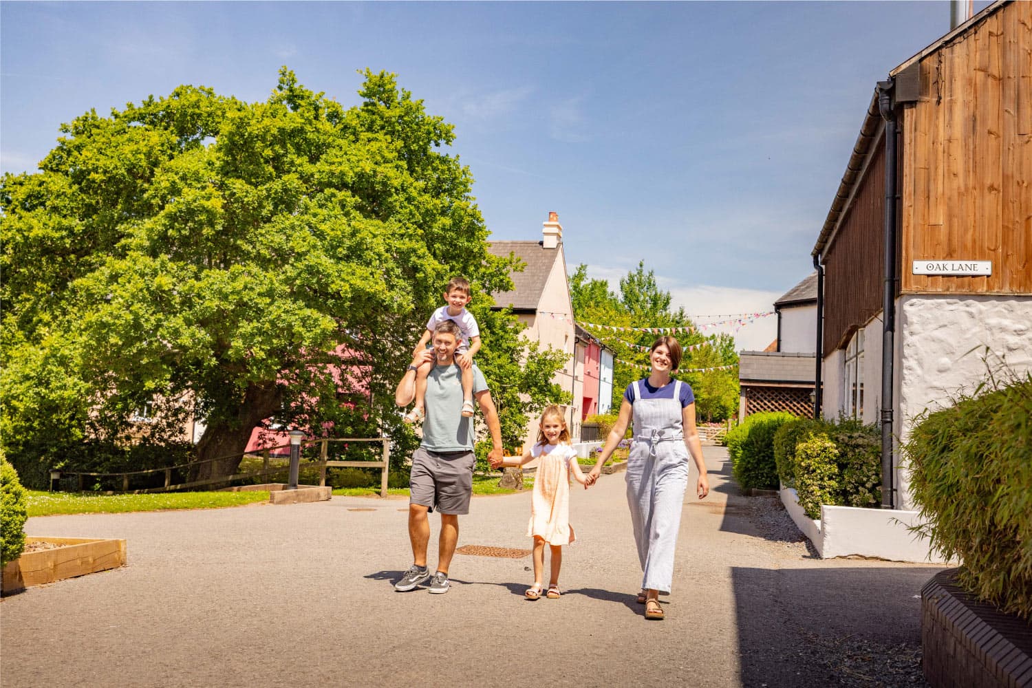 Family Walking Through The Village In Summer